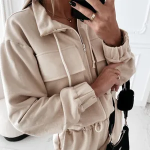 Close-up of stylish beige loose-fit two-piece tracksuit with hoodie and cargo pockets.