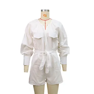 Detailed view of a white cotton linen romper with long sleeves and a belted waist