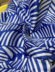 Close-up view of blue and white palm leaf print fabric with silky satin finish texture