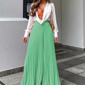Detail der minzgrünen plissierten Hose mit weitem Bein, weißem Hemd und goldener Tasche