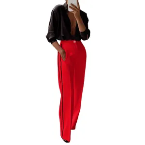 Detailweergave van stijlvolle rode wijde broek met zijstrepen op een vrouwelijk model.