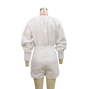 Back view of a white loose cotton linen romper with long sleeves and a belted waist