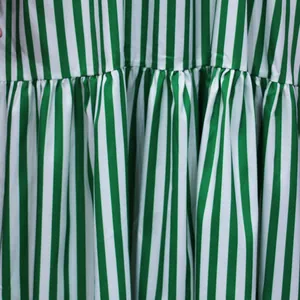 Macro close-up detail of green and white vertical striped dress fabric with pleats