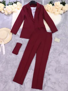 Stijlvol bordeauxrood tweedelig damespak met blazer en pantalon op luxe achtergrond