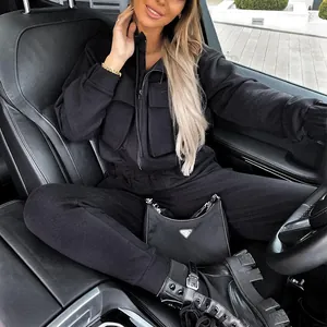 Detailed shot of a black autumn tracksuit worn by a woman sitting in a luxury car