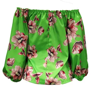 Macro view of green off-the-shoulder blouse featuring vibrant pink floral print designs.