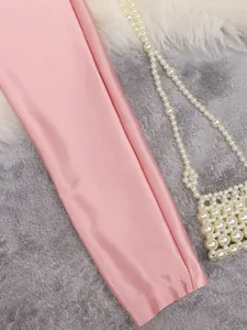 Detailed view of the smooth pink satin fabric and delicate stitching of the blouse.