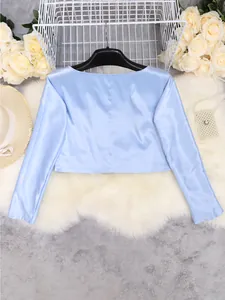 Detailed back view of a light blue satin long-sleeved crop top on a white faux fur rug