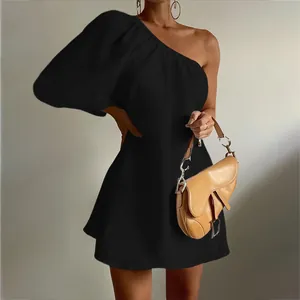 Detail view of black one-shoulder puff sleeve cotton linen mini dress with tan bag