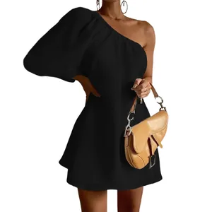 Macro view of black one-shoulder cotton linen mini dress featuring a puff sleeve detail