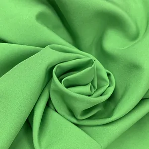 Close-up macro view of vibrant green dress fabric showing fine woven texture and drape
