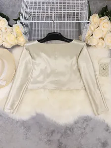 Champagne satin long sleeve crop top displayed with elegant floral and pearl accessories.