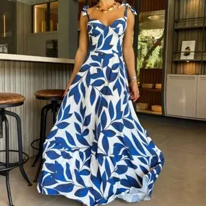 Detalle del estampado de hojas azules y los tirantes en el vestido largo blanco de mujer.