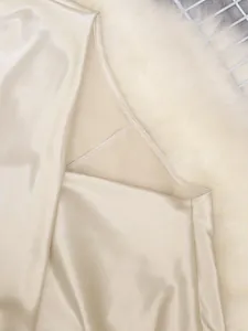 Macro detail of champagne satin top showing smooth fabric texture and neat white stitching