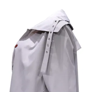 Close-up view of the decorative shoulder strap and large lapel of the grey trench coat.