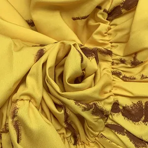 Dettaglio del tessuto giallo dell'abito bohémien con stampa marrone e dettagli increspati