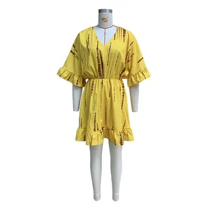 Dettaglio di mini abito bohémien giallo con motivi tie-dye marroni e maniche con volant