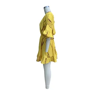 Vista laterale di un abito corto giallo bohémien con stampa tie-dye marrone su manichino bianco