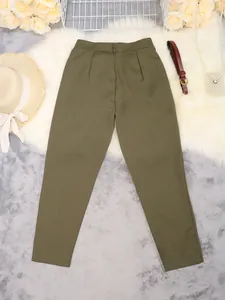 Detailed view of olive green high-waisted tapered suit pants on a white fur rug.