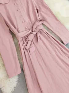 Detailed view of pink long-sleeve cotton linen dress with buttons and waist tie.