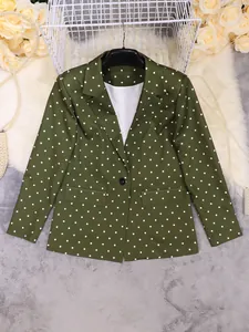 Flat lay view of a green polka dot blazer with white lapels and floral props.