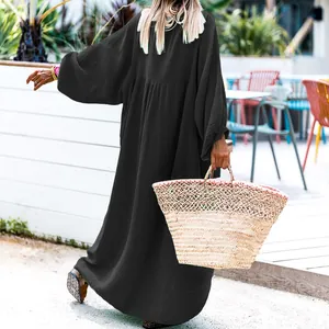 Back view of a loose black resort maxi dress with long sleeves and pleated detail.