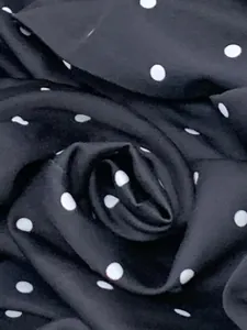 Detailed macro view of smooth black blazer fabric with elegant white polka dot pattern.