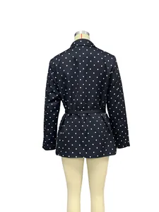 Back view of a chic navy blue polka dot blazer featuring a black waist belt detail.