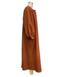 Detailed side view of a loose burnt orange long-sleeved vacation style maxi dress