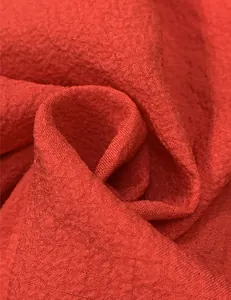 Detailed macro view of vibrant red textured bubble crepe fabric for a women's vacation dress