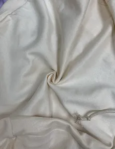 Macro view of soft beige fleece fabric texture with a woven drawstring detail for clothing
