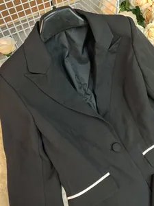 Detailed macro view of women's black blazer with notched lapel and white pocket trim