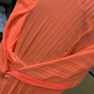 Nahaufnahme von leuchtend orangefarbenem Plissee-Stoff mit passendem Reißverschluss