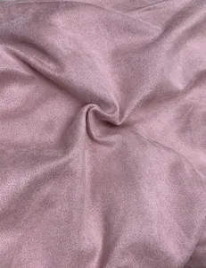 Close-up of soft pink suede fabric texture with delicate folds and matte finish.