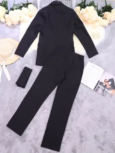 Elegant zwart tweedelig damespak met blazer en broek, gefotografeerd met accessoires.