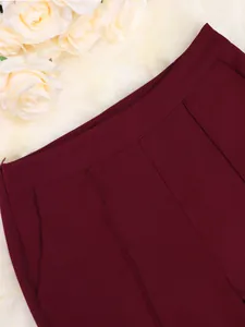 Close-up van bordeauxrode pantalon met verfijnde stoftextuur en afwerking van de tailleband