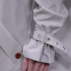 Detail view of the sleeve cuff with adjustable buckle strap on the grey trench coat