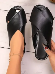 Detailed view of black criss-cross flat slippers with textured finish