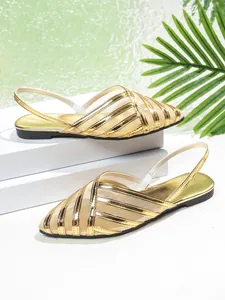 Primo piano di sandali piatti in rete dorata con un elegante design a punta sottile.