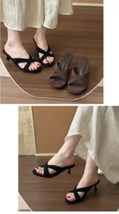 Dettaglio dei sabot minimalisti con tacco a spillo e cinturini incrociati neri per donna
