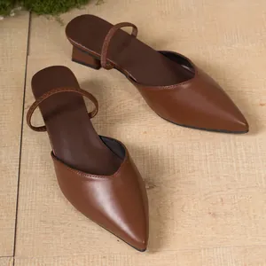 Dettaglio di sabot marroni a punta in similpelle con tacco basso ed elegante stile.
