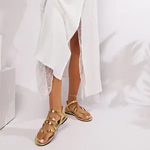 Detail of gold flat gladiator sandals with cross-straps and toe-loop on feet