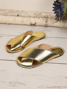Macro view showing the metallic snakeskin texture of these golden cross-strap slippers