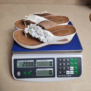 Gedetailleerde gewichtsmeting van witte sleehak teenslippers met bloemen, 200 gram op schaal