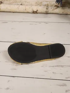 Close-up detail of the black anti-slip rubber sole on a gold closed-toe mule slipper