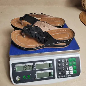 Lichte zwarte sleehak-slippers met bloemendetails op een digitale weegschaal