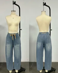 Vue détaillée de jean vintage délavé avec cordon de serrage et taches de peinture blanche.