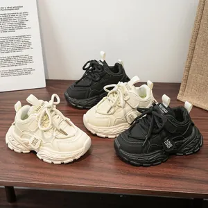 Baskets chunky pour enfants en noir et blanc cassé présentées sur une table en bois