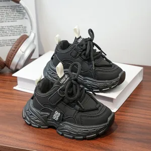 Baskets épaisses noires tendance pour enfants présentées dans un décor moderne.
