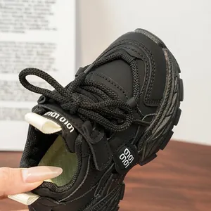 Gros plan de la basket de course noire pour enfant avec tige en mesh et lacets